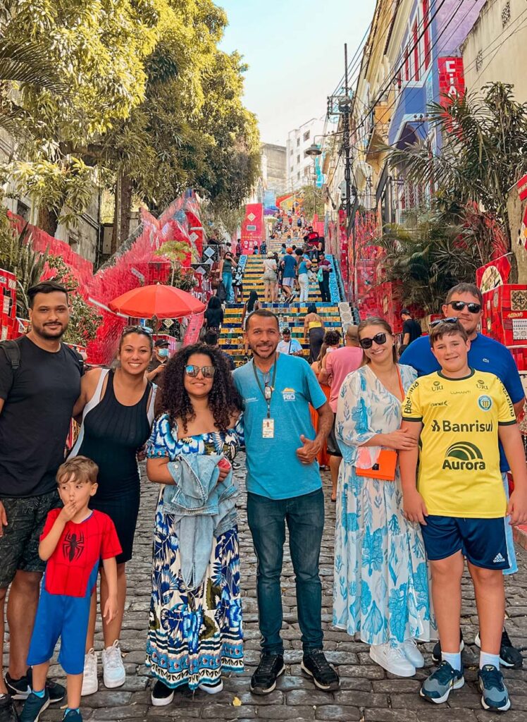 Grupo de turistas sorridentes na Escadaria Selarón com guia credenciado da Passeio Rio, comprovando a experiência e segurança do tour.